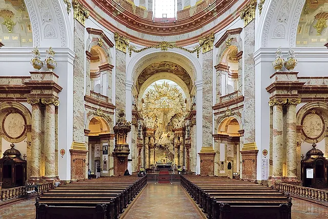 O interior da Karlskirche, com fileiras de bancos de madeira que levam, entre pilares de mármore, à glória dourada sobre o altar-mor