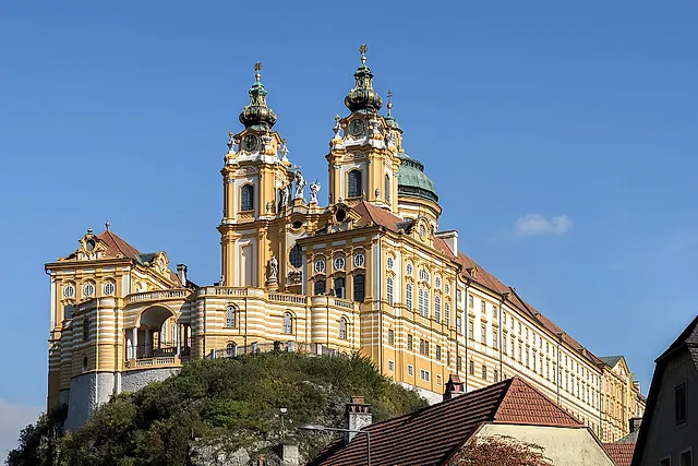 A abadia barroca de Melk, com as duas torres e a cúpula da igreja, sobre seu rochedo, sob um céu de azul intenso
