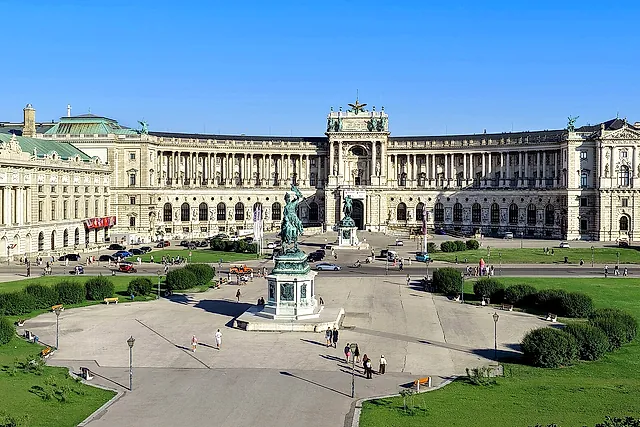 A Praça dos Heróis (Heldenplatz) vista de cima, com suas estátuas equestres e a fachada curva da Neue Burg, parte da Hofburg, sob um céu azul